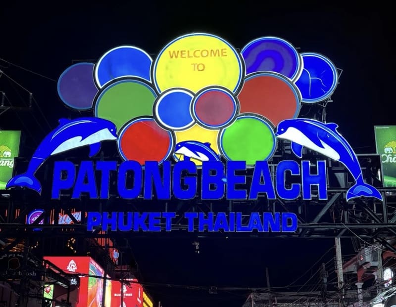 Beleuchtetes Neonschild von Patong Beach in Phuket, mit bunten Lichtern und Delfin-Figuren bei Nacht
