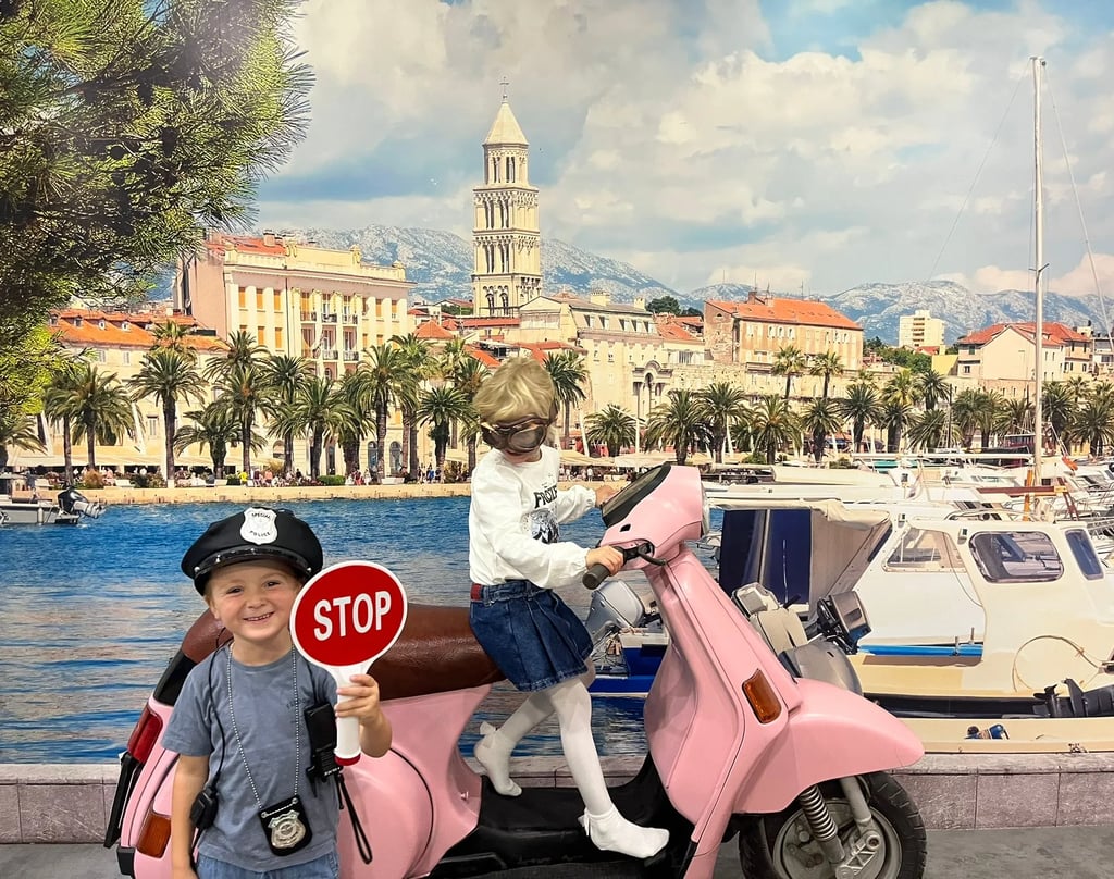 a young boy riding a pink scooter