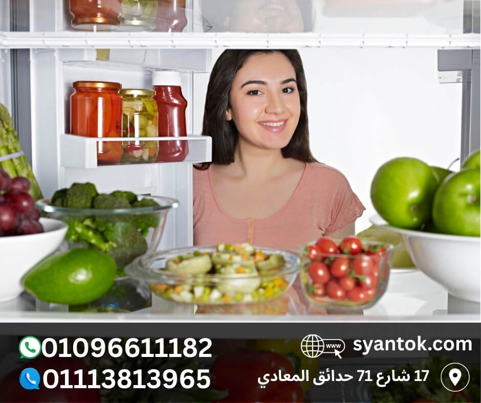 <img src="your-image.jpg" alt="سيدة تبتسم أمام ثلاجة مفتوحة مليئة بالخضروات والفواكه الطازجة، إعلان يحتوي على أرقام تليفون وع