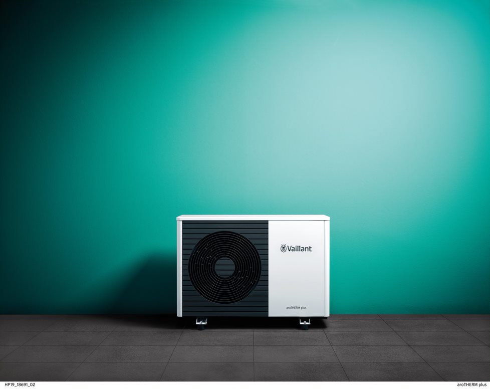 a white and black heat pump with a green wall