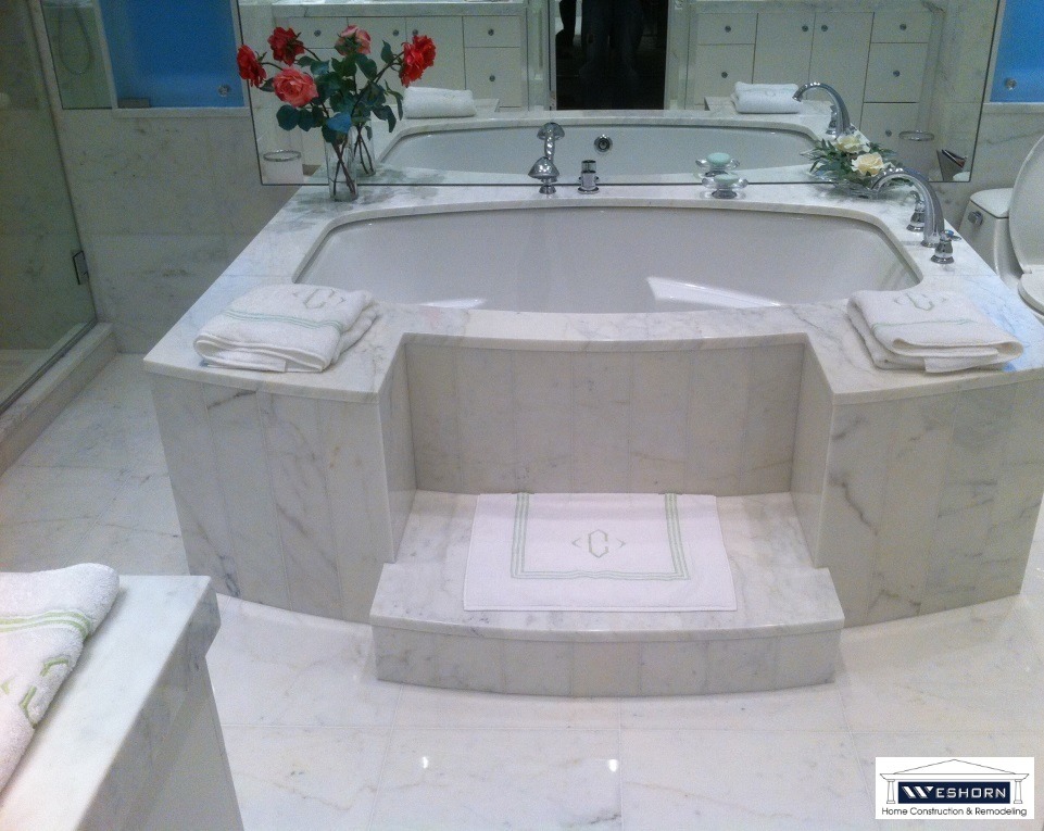 Luxury white marble bathtub with custom stone tile steps and elegant bathroom decor.