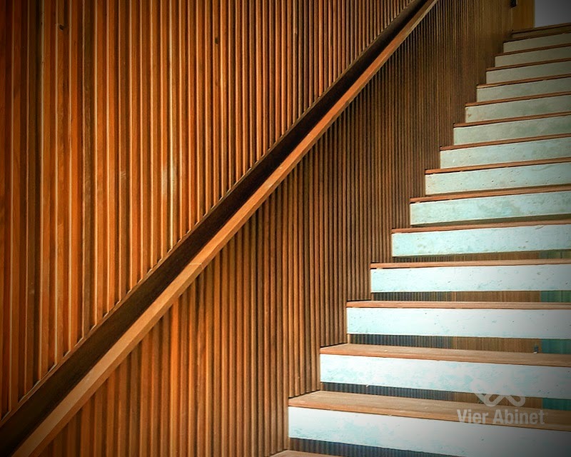 Escalera interior moderna con revestimiento de pared con listones de madera verticales.
