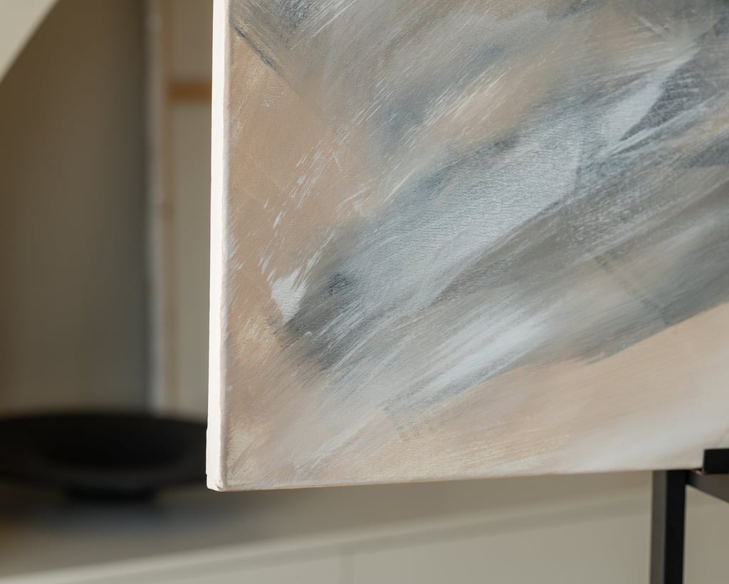 Close-up of an abstract acrylic painting featuring neutral grey, white, and beige brushstrokes on canvas.