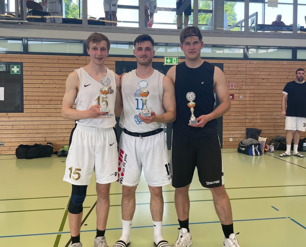 alt="Three basketball players displaying their individual trophies."