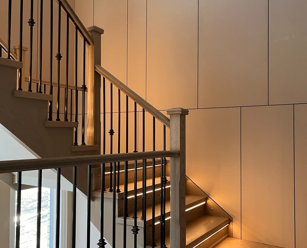 Modern interior oak staircase with LED step lighting and elegant black iron balusters.