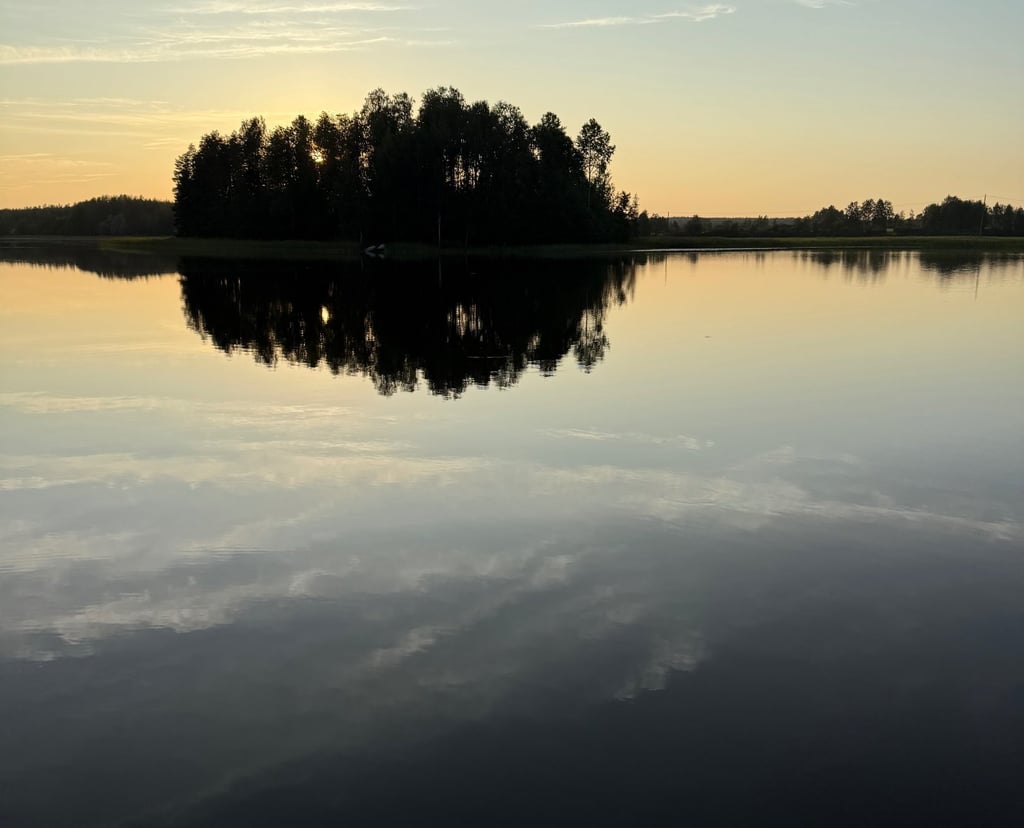 a lake with a few trees and a sky