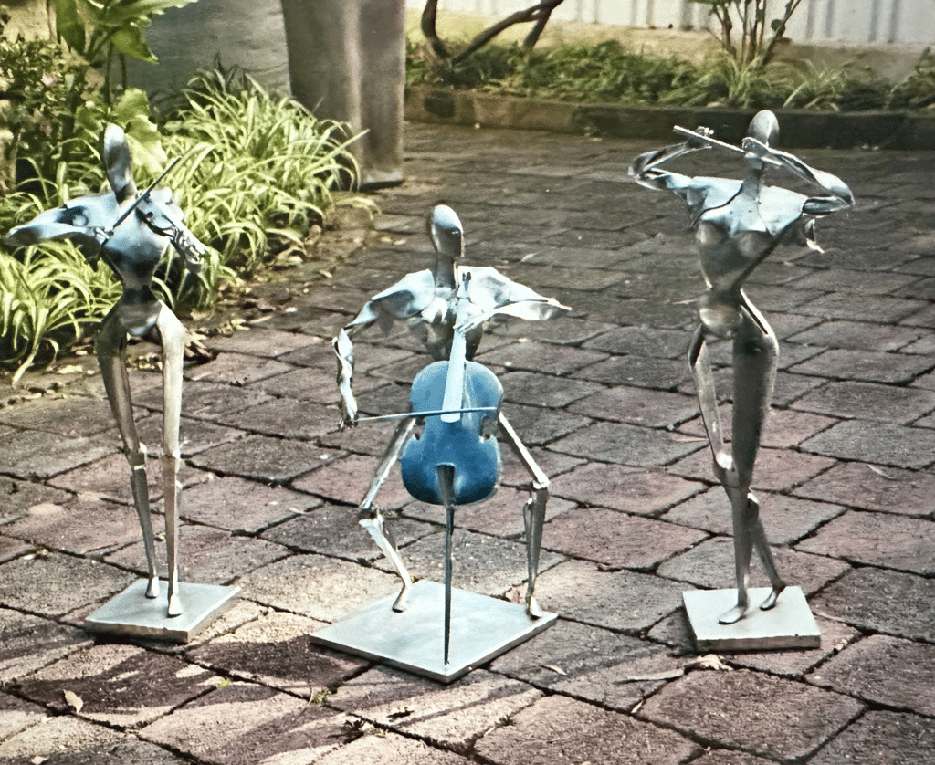 three statues of robot like musicians playing instruments