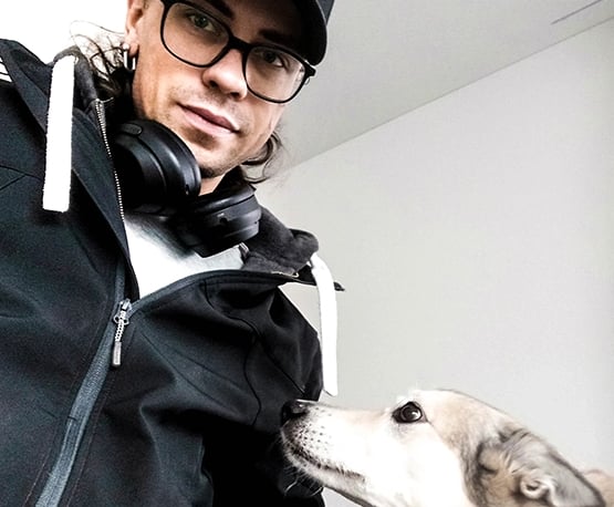 lächelnder Mann mit Brille und schwarzer Baseballkappe mit grauem Hund