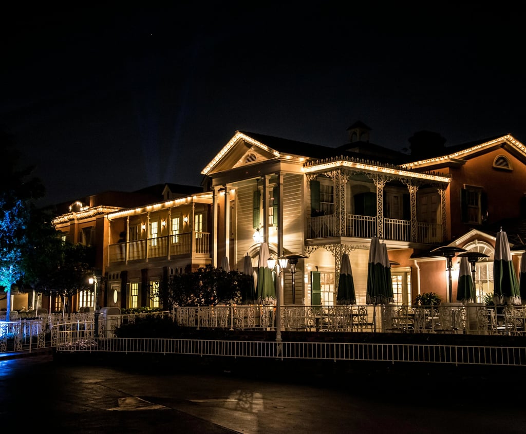 Colonial-style buildings lit with warm string lights at night featuring an outdoor patio.