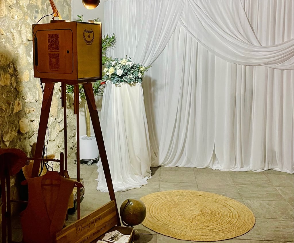 Photobooth en bois vintage installé lors d’un mariage, intégré dans une scénographie élégante avec r