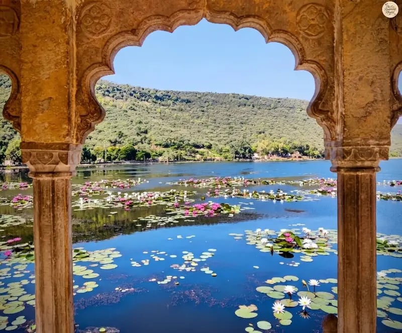 View of Jait Sagar Lake framed through the ornate arches of Sukh Mahal in Bundi.
