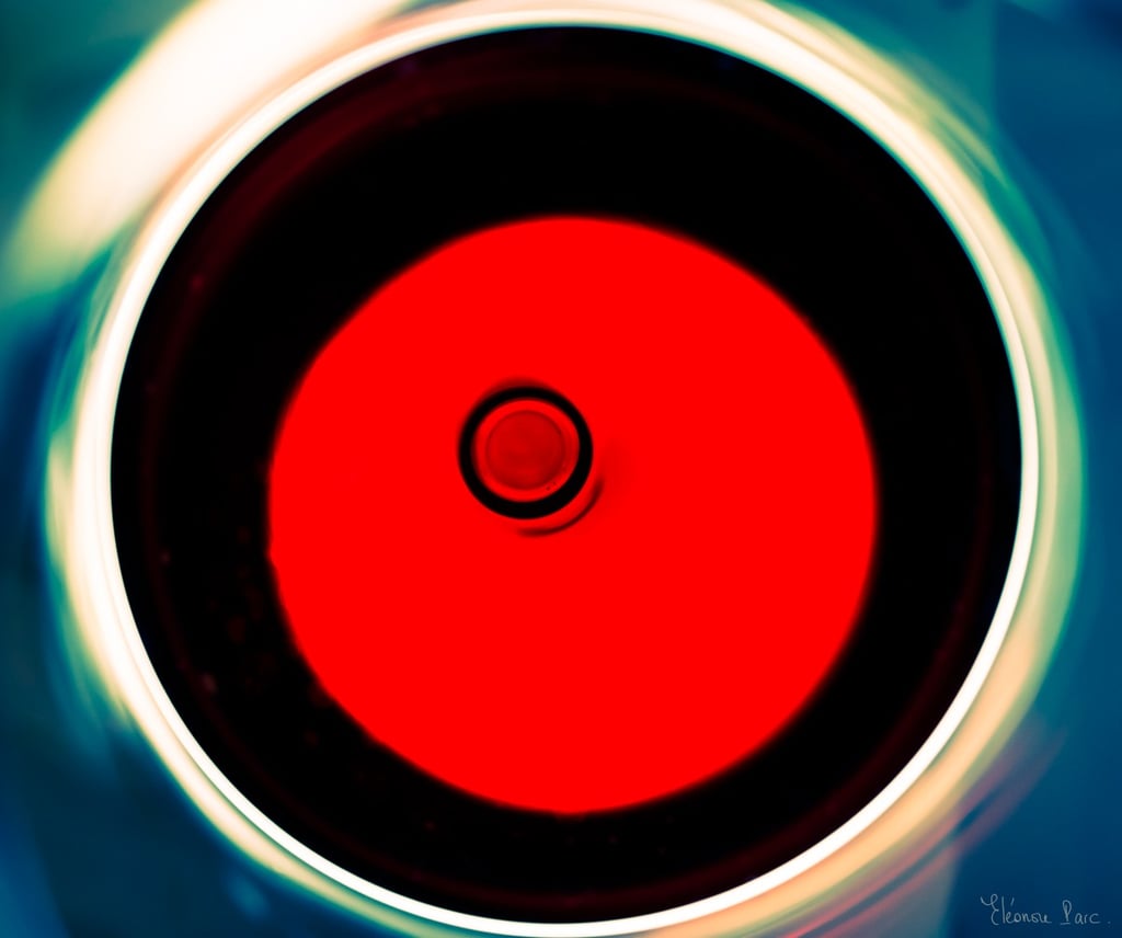 Abstraction Vinicole – Verre de vin vu du dessus, disque rouge et anneaux lumineux