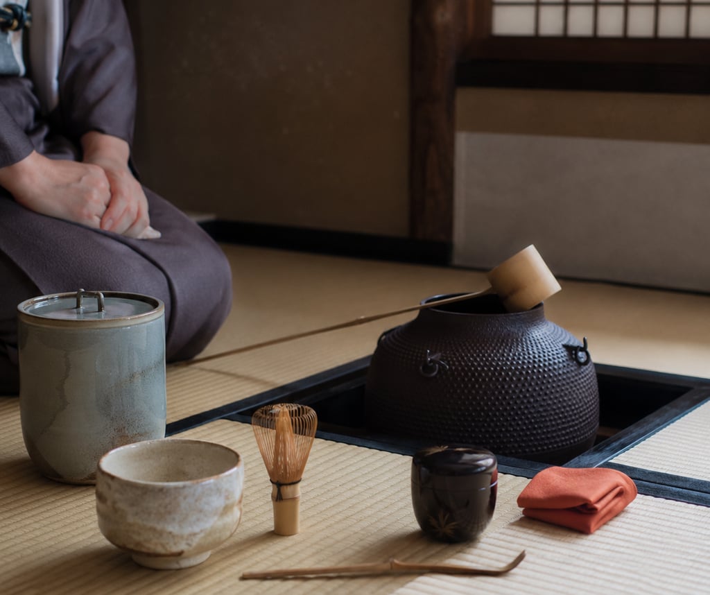 Traditional Japanese tea ceremony set with matcha whisk, bowl, and iron kettle on tatami mat.