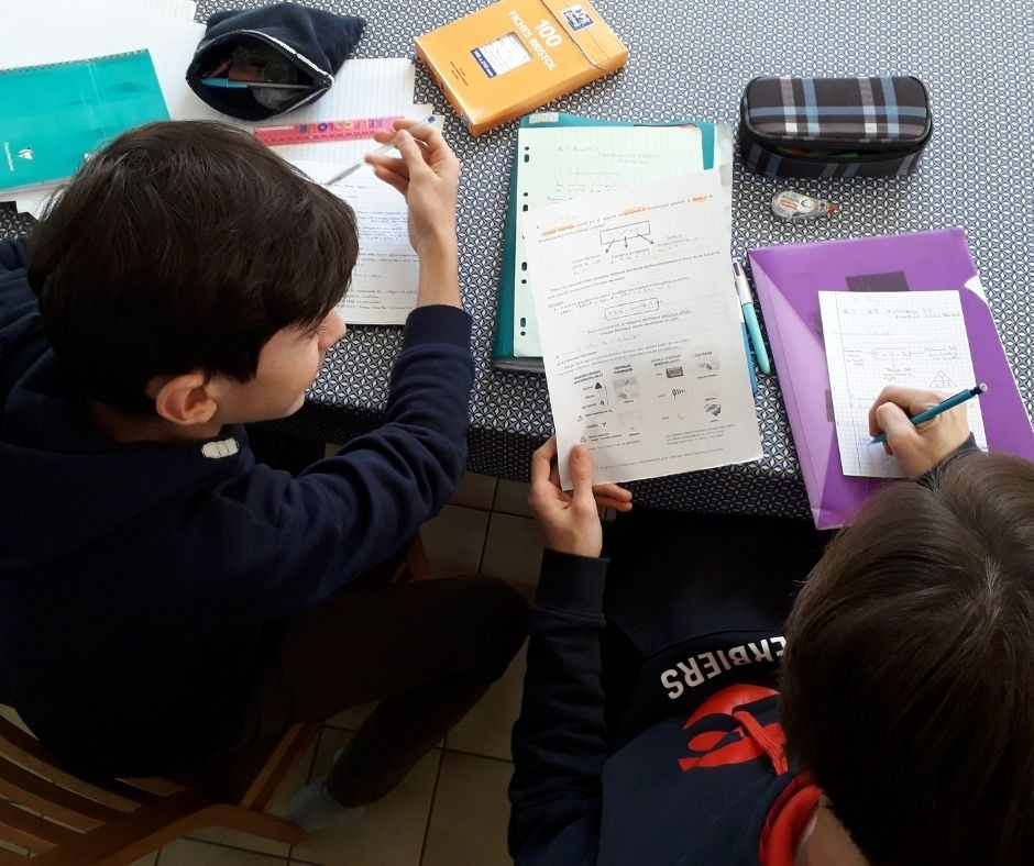 two boys sitting at a table with notebooks