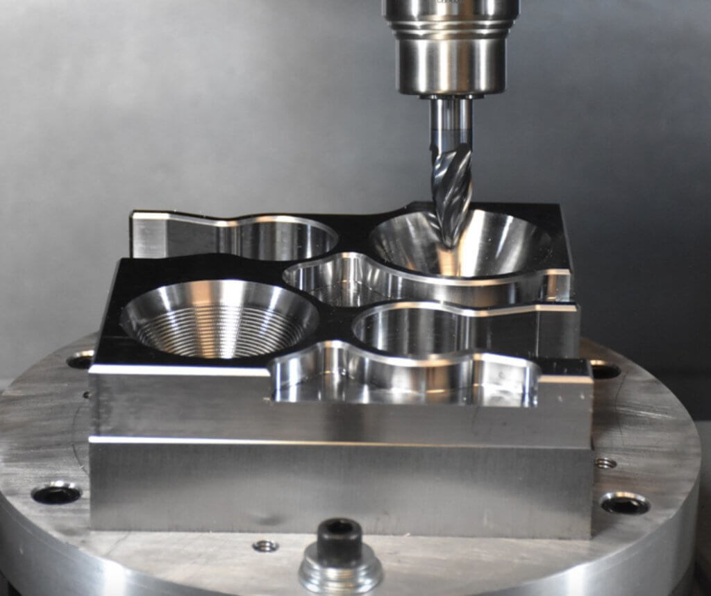 A precision CNC milling machine drills into a polished metal part for industrial manufacturing.