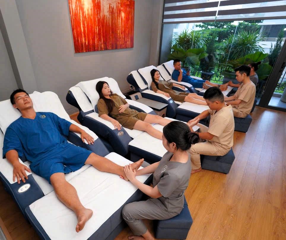 a group of people sitting in a row of beds in a spa and getting a massage