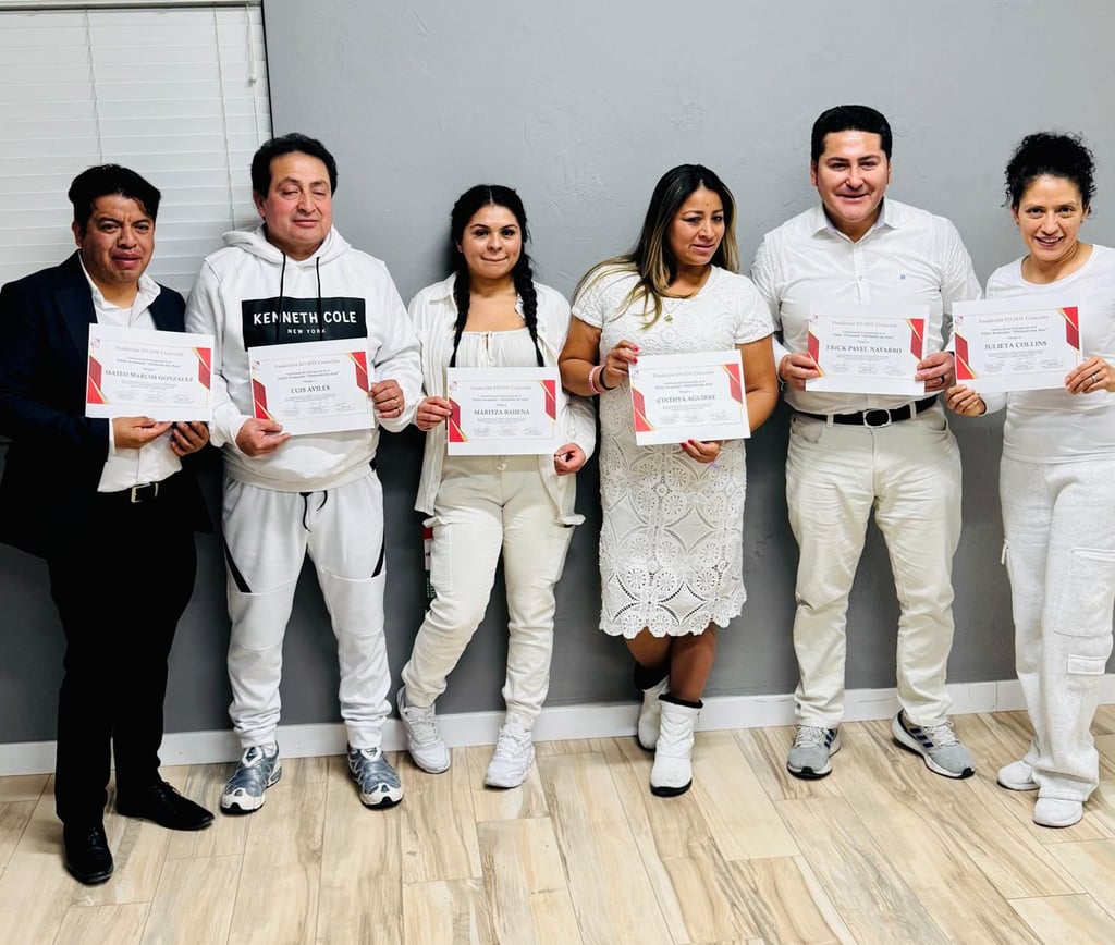 A group of smiling graduates posing together while holding their professional certification awards.