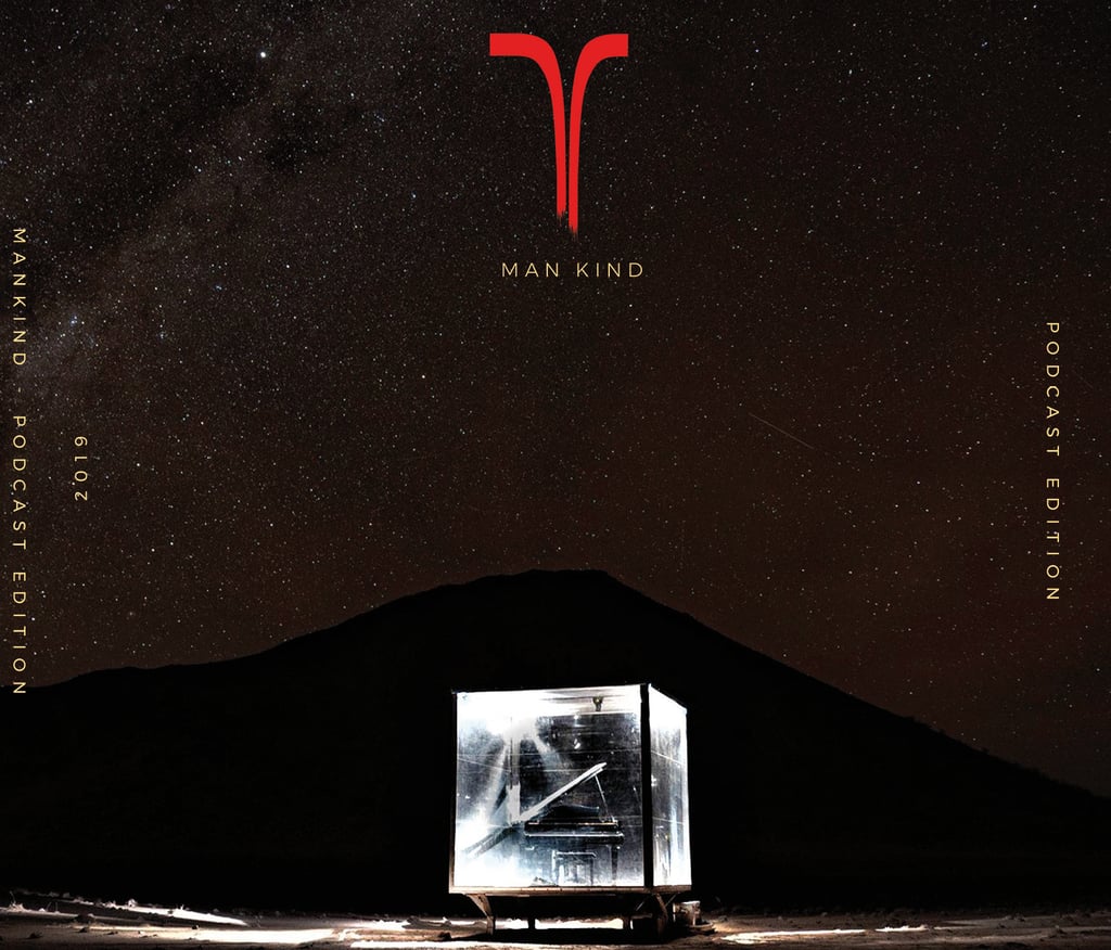 a man in a cube playing a grand piano in front of a mountain
