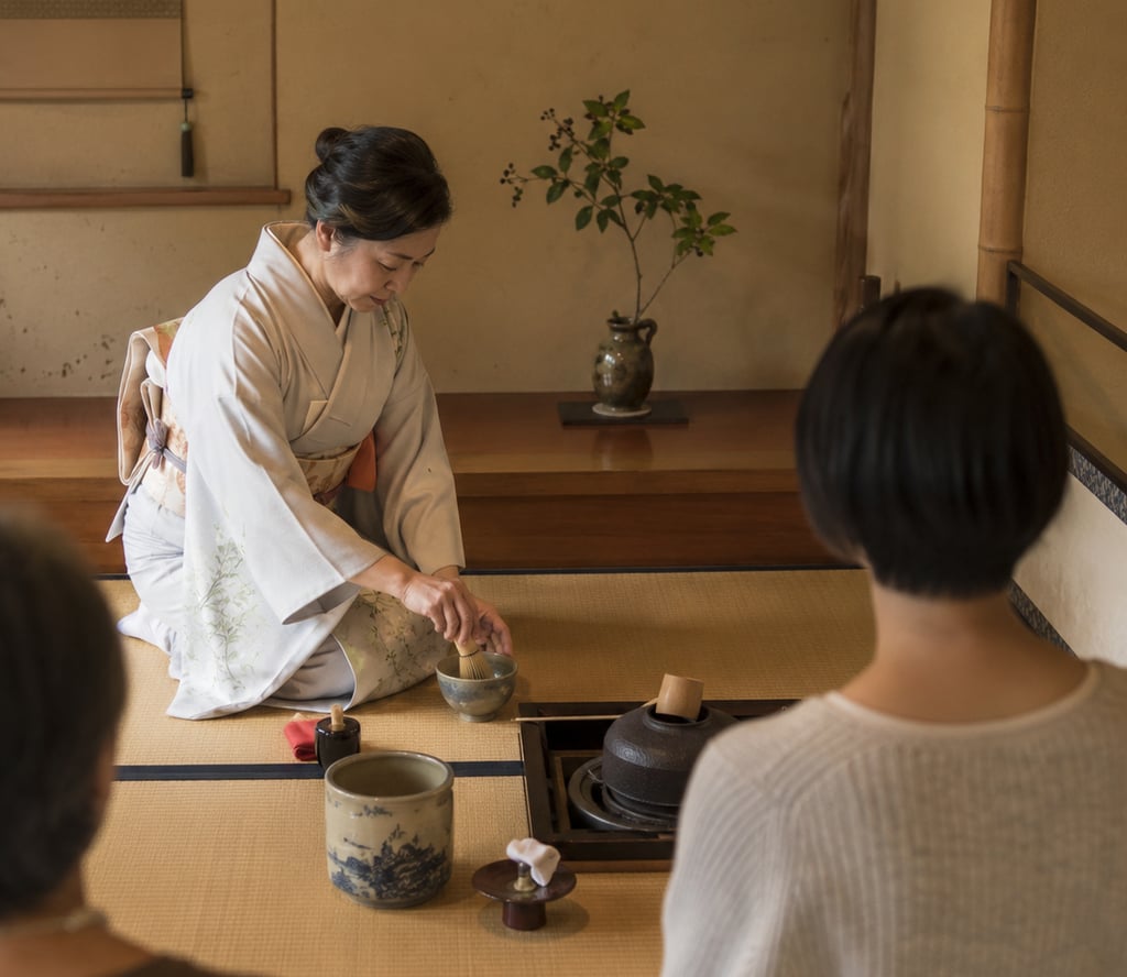 A Japanese woman in a kimono performs a traditional matcha tea ceremony on a tatami mat.