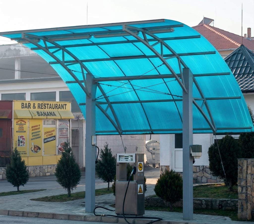 A single gas pump station under a curved blue polycarbonate canopy near a restaurant.