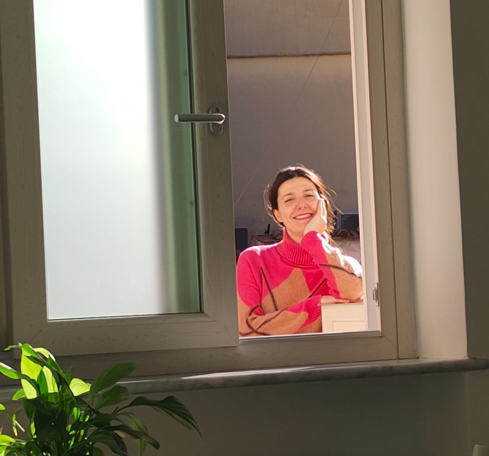 Giusy smiling through the window of the new home in Amalfi, in the first days