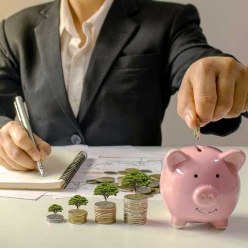 imagem mostra um executivo colocando uma moeda no cofrinho fazendo ideia de economizar poupar