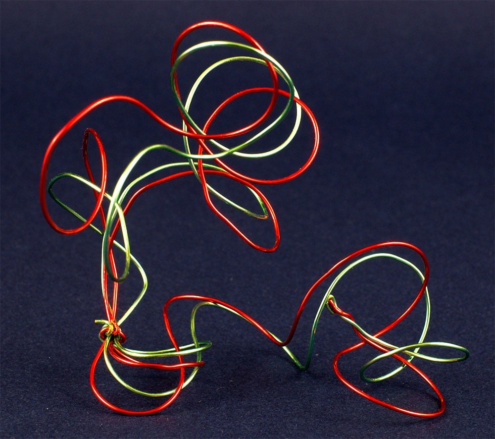 Abstract metal wire sculpture of a person kicking a soccer ball