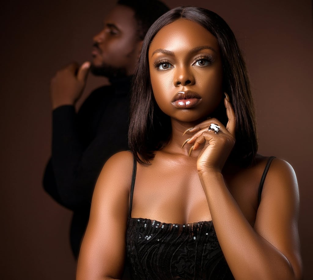 Confident Black woman in deep thought with man blurred in background,
