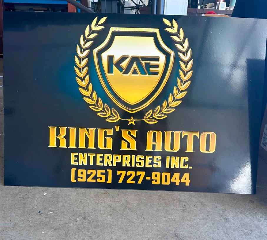 Custom black and gold King's Auto Enterprises sign featuring a shield logo and contact number.