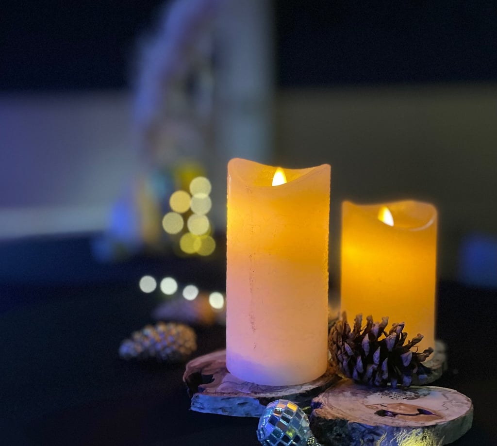 Détail de décoration de mange-debout avec bougies LED effet cire, rondins de bois, pommes de pin, bo