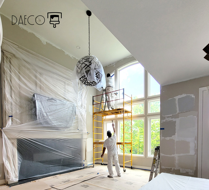 two painters in painter whites painting large living room