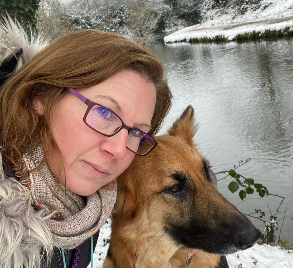 A woman and her German Shepherd dog resting cheek to cheek, sharing a calm and connected moment