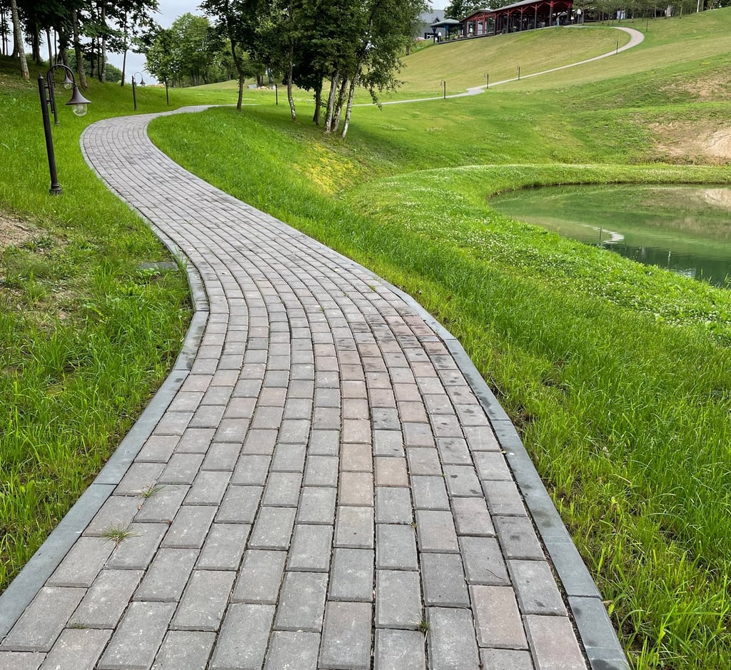 a brick paved path with a path leading to a grassy area