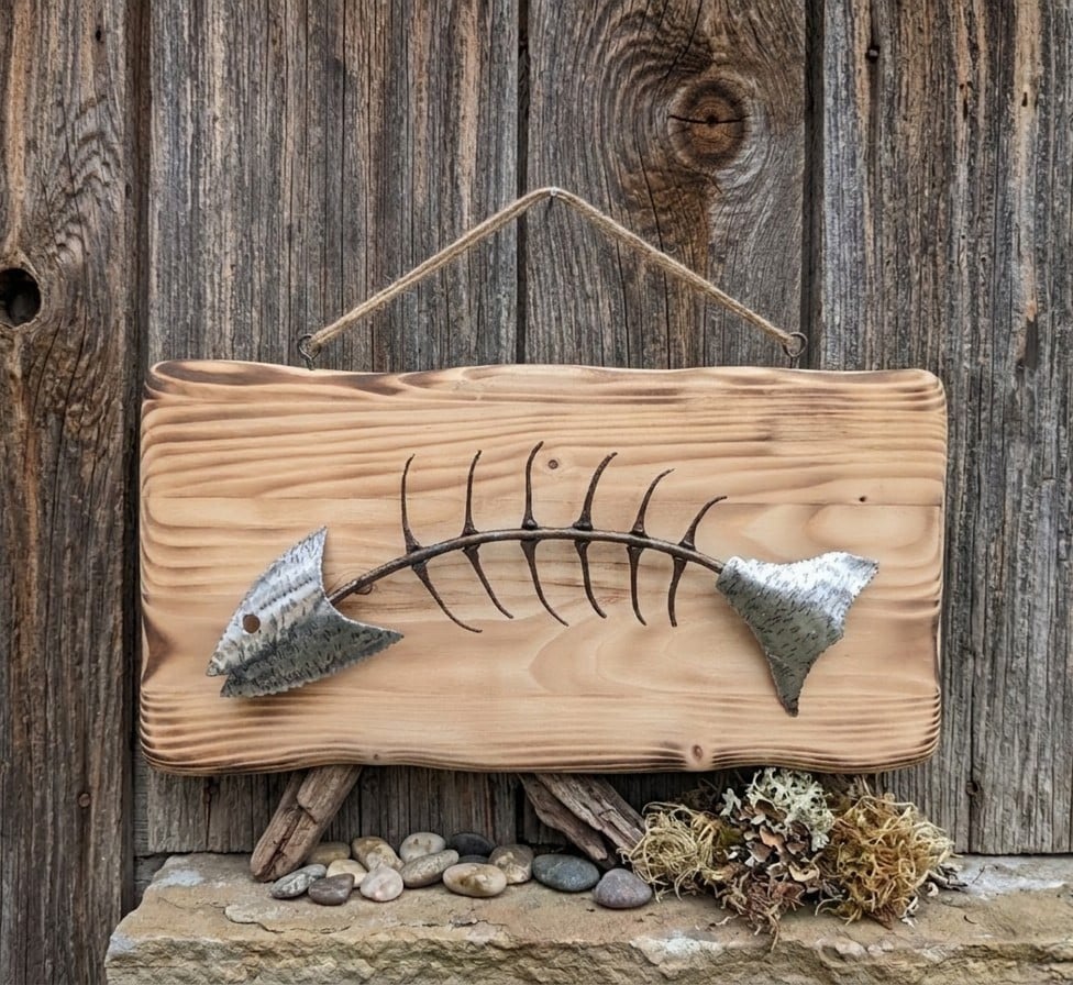 Hanging wall art of a fish made from recycled metal materials and horseshoe pins on a wood frame