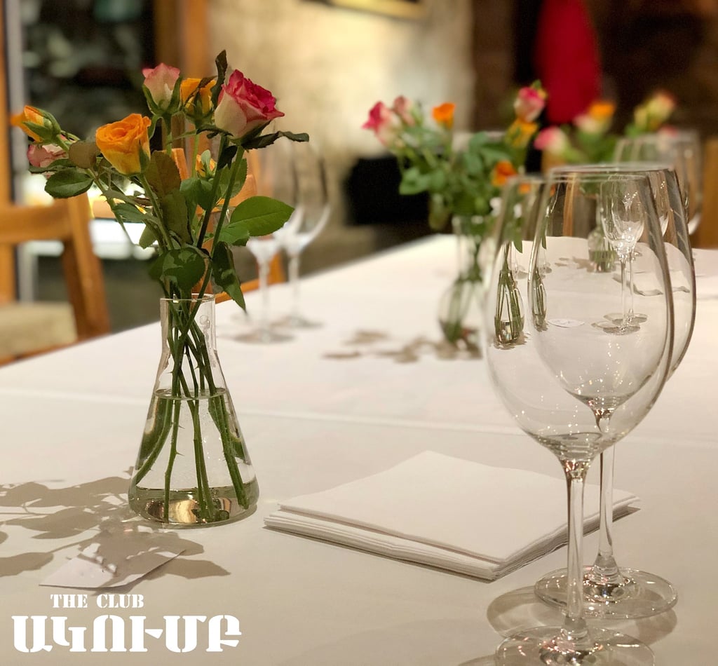Elegant restaurant table setting with fresh rose flower centerpieces and crystal wine glasses.