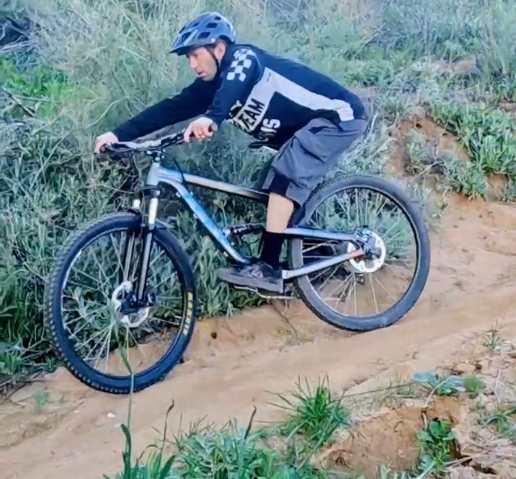 Mountain biker riding down steep trail on a trail bike full suspension