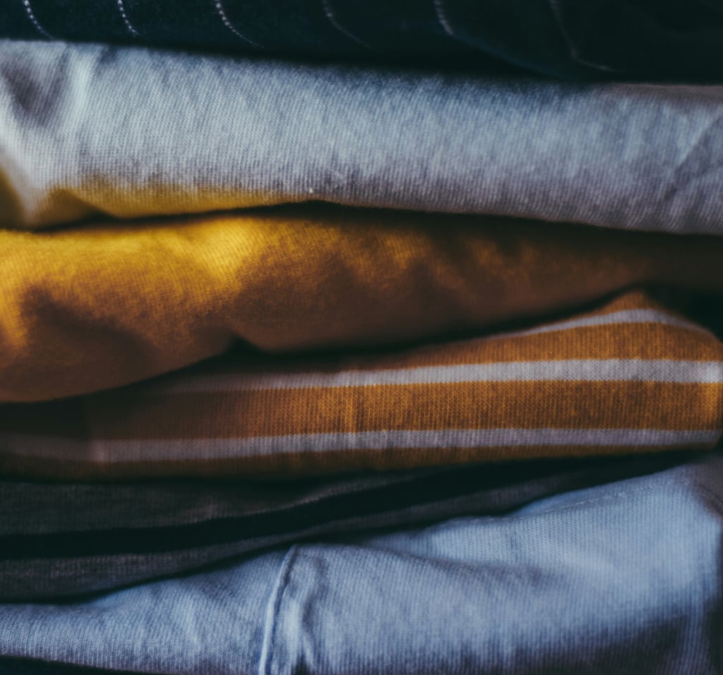Close-up of neatly folded clothes in soft fabrics and warm colors.