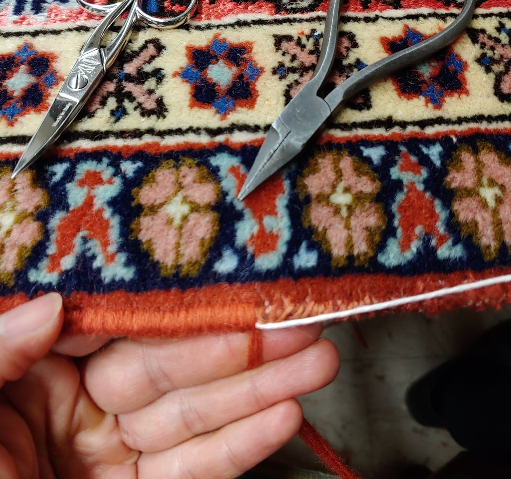 restauratore che esegue con maestria la ricostruzione dei bordi su un tappeto