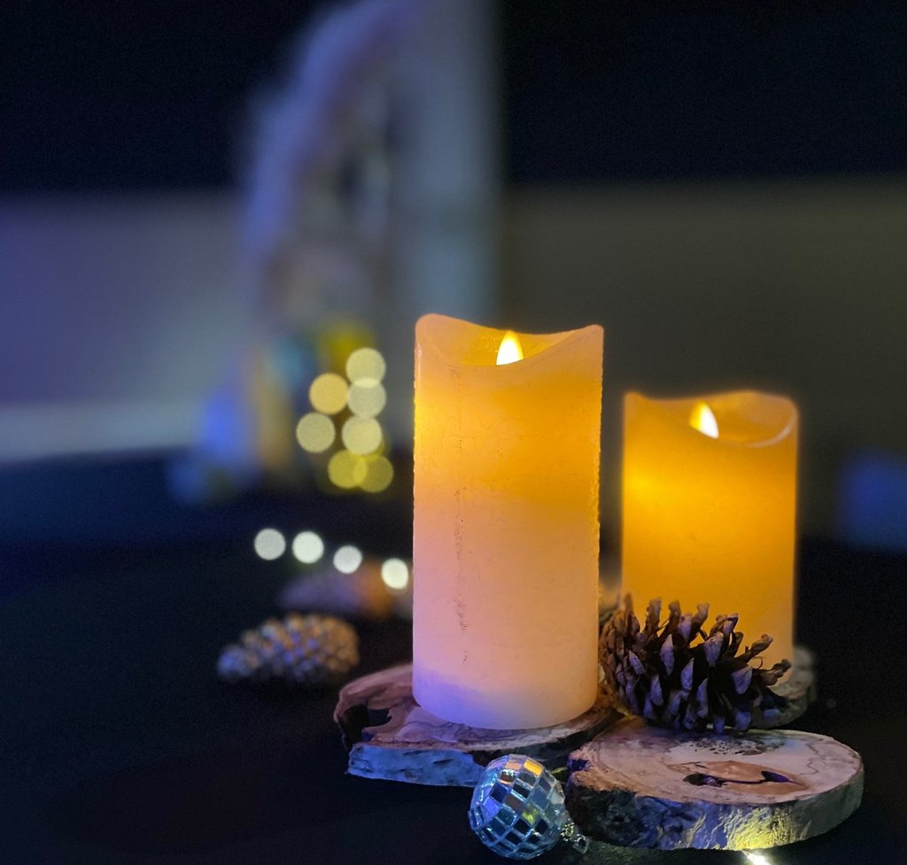 Détail de décoration de mange-debout avec bougies LED effet cire, rondins de bois, pommes de pin, bo