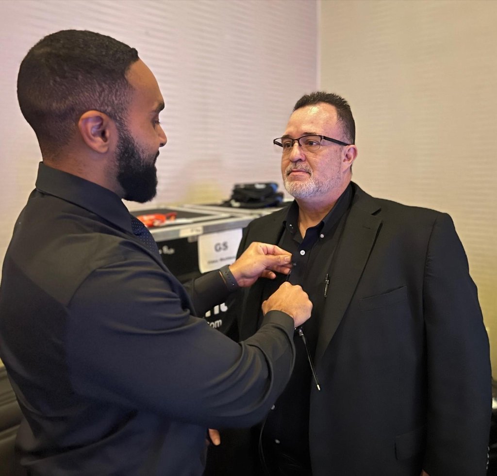 a man in a suit and glasses is getting mic'd up