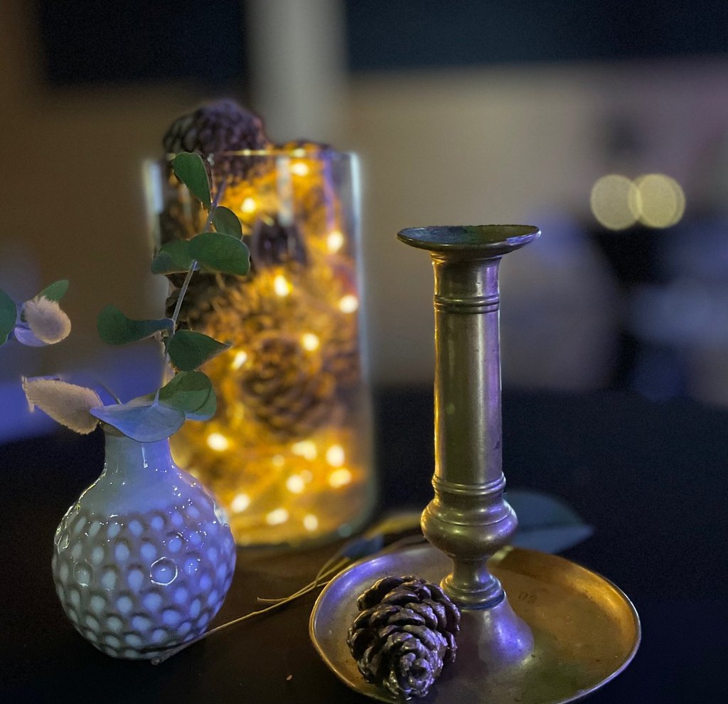 Composition décorative pour mange-debout avec bougeoir en laiton, vase texturé, eucalyptus, pommes d