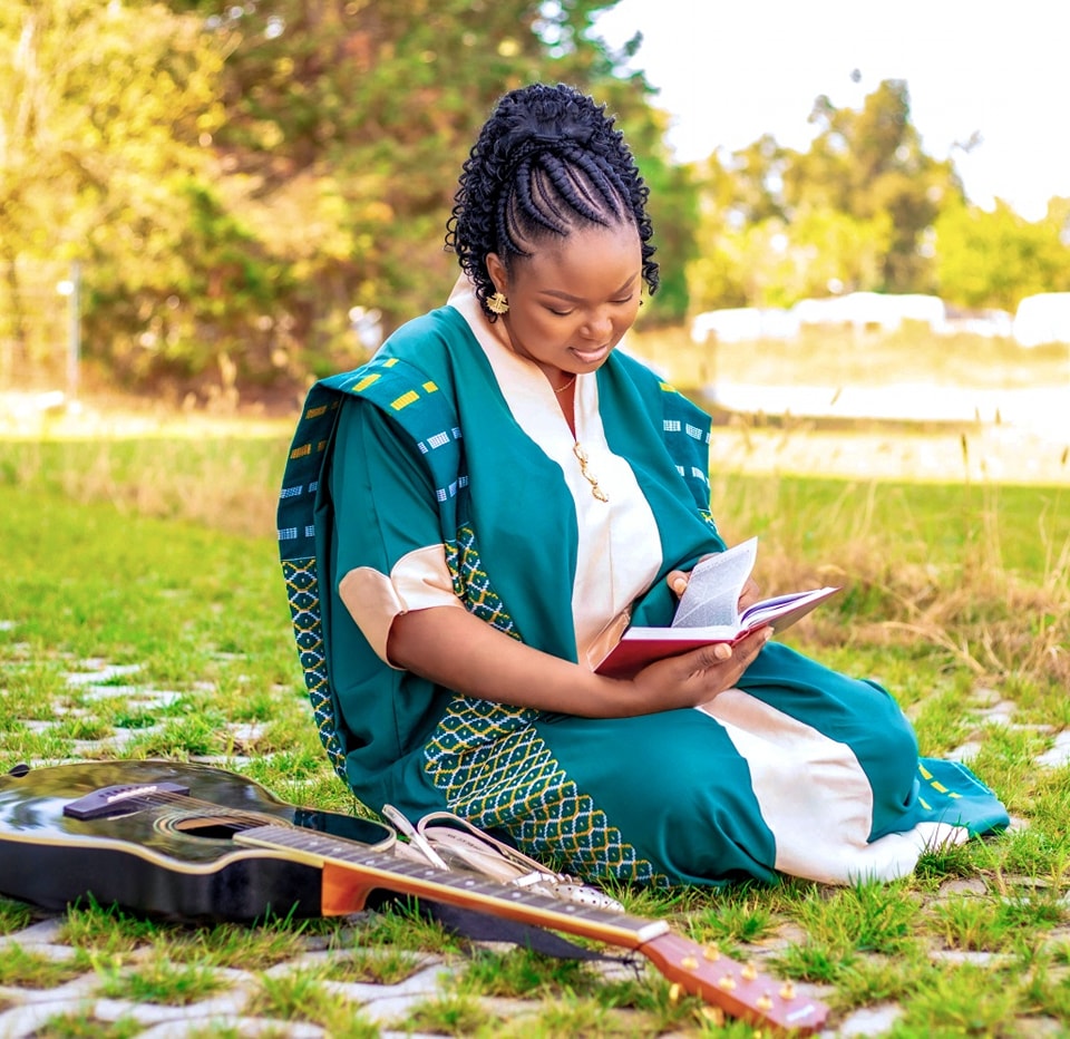 a woman sitting on the grass with a guitar