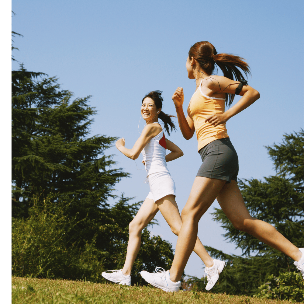 two women running in the grass with trees in the background