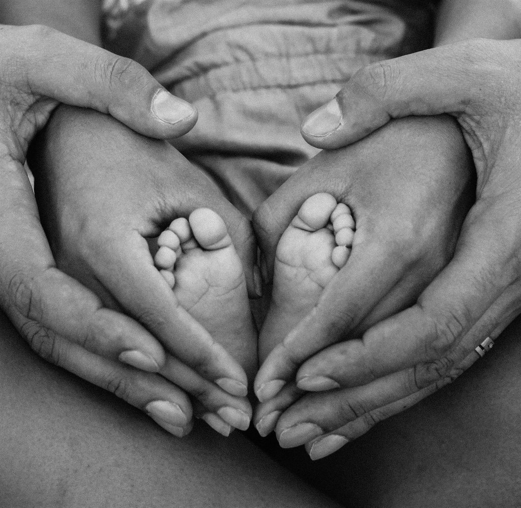 Parents holding babies feet in a heart shape