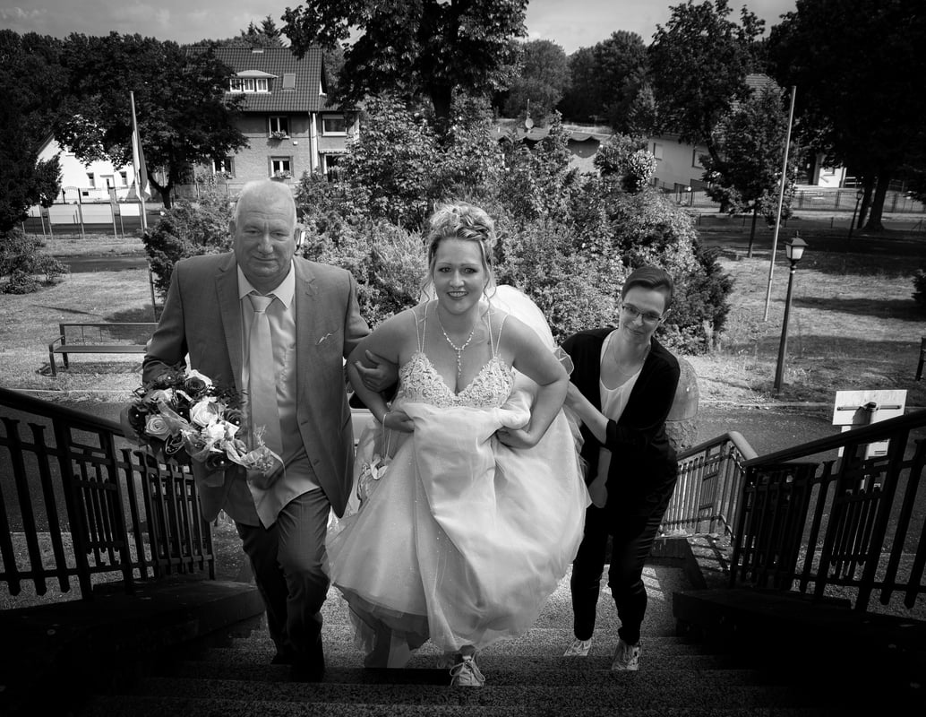 a bride and groom walking down stairs in a black and white photo