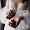 a woman in a white dress holding a red perfume bottle
