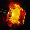 a person holding a piece of amber with a yellow light