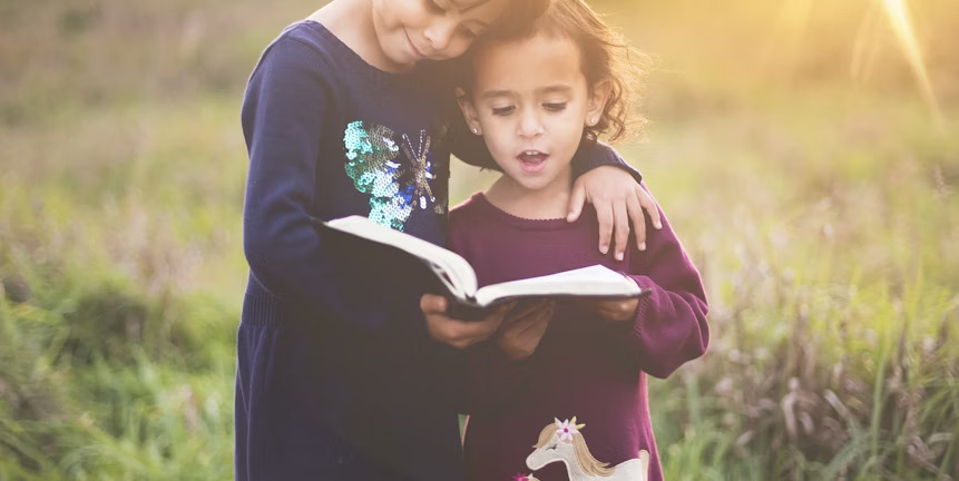 A child reading a book with an adult in a natural setting