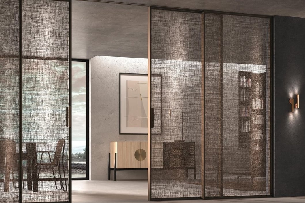 Separación de ambientes con puertas correderas de cristal en espacio cálido con materiales naturales