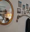 a mirror reflecting a wall with a coat rack and a nature pictures